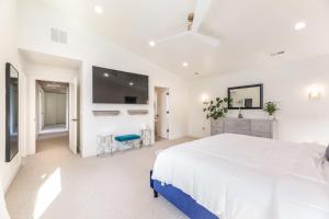 a white bedroom with a large bed and a flat screen tv at BRAND NEW Modern 5 Bd, 3 Story Home in Sugarhouse! in Salt Lake City