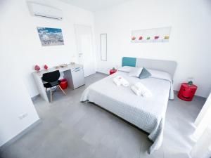 a white bedroom with a bed and a desk at Appartamento al centro storico in Caltagirone