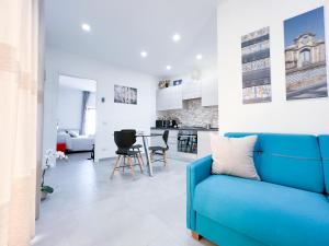 ein Wohnzimmer mit einem blauen Sofa und einer Küche in der Unterkunft Appartamento al centro storico in Caltagirone