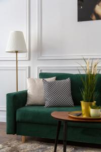 a green couch in a living room with a table at Luxurious Prestige Residence next to the New York Café in Budapest