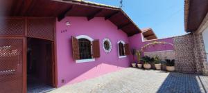 a pink house with some plants on it at Casa Rosa de Peruíbe - Casa de Temporada 3 dormitórios, 10 hóspedes, piscina, wi-fi, netflix, 800 metros da praia in Peruíbe
