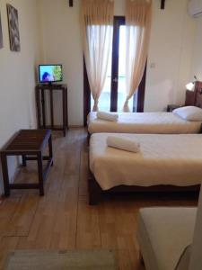 a room with three beds and a tv and a table at Philoxenia in Kavála