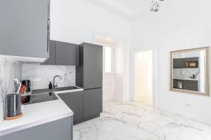 a white kitchen with black appliances and marble floors at Luxurious Prestige Residence next to the New York Café in Budapest