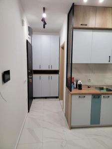 a kitchen with white cabinets and a large tile floor at Brand new apartment in Downtown Gevgelija in Gevgelija