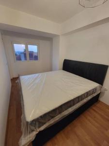 a large bed in a room with two windows at Brand new apartment in Downtown Gevgelija in Gevgelija