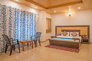1 dormitorio con 1 cama, mesa y sillas en The Himlayan Trails I Serviced Apt I Balcony I Nature View I Kasauli By Exotic Stays, en Kasauli
