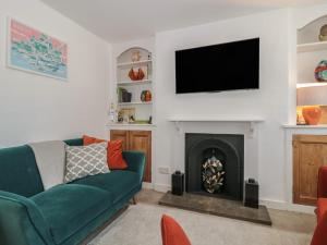 a living room with a green couch and a fireplace at Mollys Cottage in Dorchester