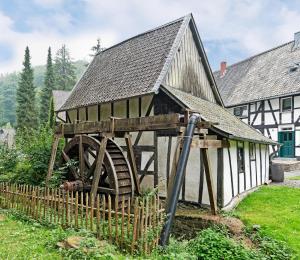 een oude molen met een waterrad voor een gebouw bij Cozy Inn Schladern in Windeck