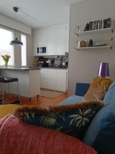 a living room with a blue couch and a kitchen at Rauhallinen kaksio Urpolassa in Mikkeli