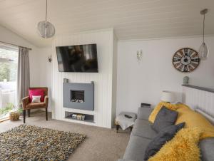 a living room with a couch and a tv at 32 Sanctuary Lodge in Pwllheli
