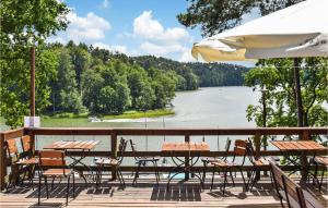 a deck with tables and chairs and a view of a river at Awesome Home In Ruciane - Nida With Kitchen in Ruciane-Nida