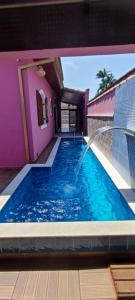a swimming pool with a fountain in a pink house at Casa Rosa de Peruíbe - Casa de Temporada 3 dormitórios, 10 hóspedes, piscina, wi-fi, netflix, 800 metros da praia in Peruíbe