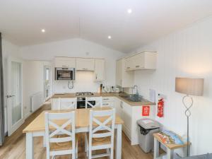 a kitchen with white cabinets and a wooden table and chairs at Lodge 19 - Isla Hideaway in Perth