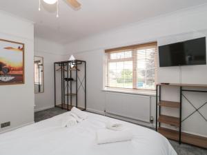 um quarto com uma cama branca e uma televisão de ecrã plano em Seabar em Burnham on Sea
