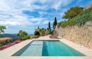 una piscina con 2 tumbonas junto a una pared de piedra en Awesome Home In Puigpunyent With Outdoor Swimming Pool And 3 Bedrooms, en Puigpunyent