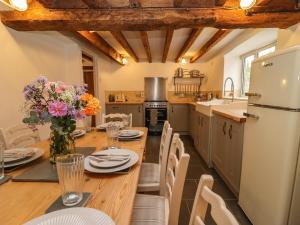 a kitchen with a wooden table with chairs and a refrigerator at 1 White House Cottages in Ross on Wye