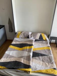 a bed with a yellow and gray comforter in a room at Magnifique studio à Anzère avec vue sur les montagnes in Anzère