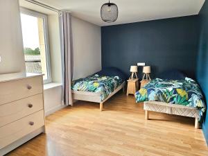 2 camas en un dormitorio con paredes azules y suelo de madera en les chambres d'hôtes la Guiberdière, en Castilly