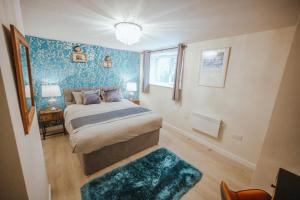 a bedroom with a bed with a blue wall at KENDAL HOLIDAY FLATS in Kendal