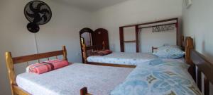 a bedroom with two beds and a mirror at Casa Rosa de Peruíbe - Casa de Temporada 3 dormitórios, 10 hóspedes, piscina, wi-fi, netflix, 800 metros da praia in Peruíbe +42 photos