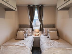 Duas camas num pequeno quarto com uma janela em Woody Ray em Bridlington