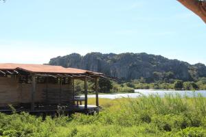 a building with a roof next to a body of water at Iharana Bush Camp in Ambondromifehy