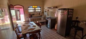 a kitchen with a table and a refrigerator at Casa Rosa de Peruíbe - Casa de Temporada 3 dormitórios, 10 hóspedes, piscina, wi-fi, netflix, 800 metros da praia in Peruíbe