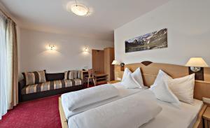 una camera d'albergo con letto e divano di Hotel Pfandleralm a San Martino