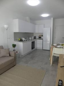 una cocina con armarios blancos y un sofá en una habitación en 19 Piso céntrico, nuevo y bien equipado en La Trinidad, en La Laguna