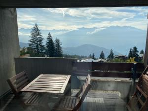 a wooden table and chairs on a balcony with mountains at Magnifique studio à Anzère avec vue sur les montagnes in Anzère