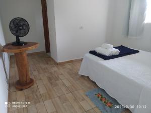 a room with a bed with a fan and a wooden table at Chalé Canto do Sabiá in Ibicoara