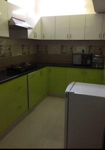 cocina con armarios verdes y blancos y nevera en AR HOME STAY, en Chennai