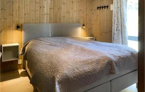a bedroom with a large bed with a wooden wall at Gorgeous Home In Bjorli With House A Panoramic View in Bjorli