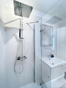 a white bathroom with a shower and a sink at Apartament Neon in Szczecin