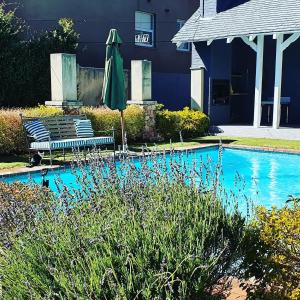 a swimming pool with chairs and an umbrella next to a building at Treehouse on Maple in Johannesburg