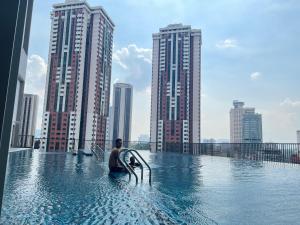 un hombre sentado en una piscina con una tabla de surf en una ciudad en Chambers luxury suites KLCC en Kuala Lumpur