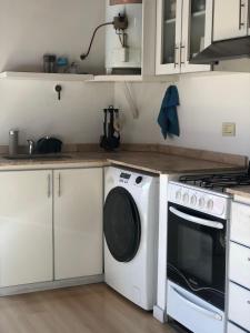 a kitchen with a stove and a washing machine at Departamento de Noah in Guaymallen