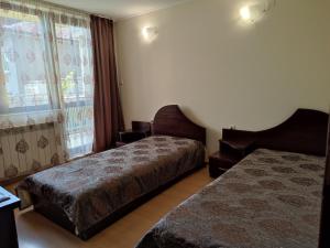 a hotel room with two beds and a window at Къща за гости M-Stone in Bansko