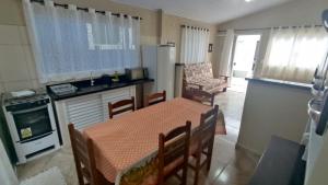 uma cozinha com mesa e cadeiras e uma cozinha com frigorífico em Recanto Primavera Ubatuba em Ubatuba
