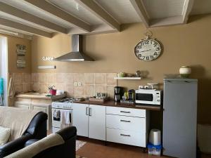 a kitchen with white cabinets and a clock on the wall at La belle Charentaise in Vaux-Rouillac