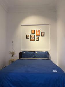 a bedroom with a blue bed with pictures on the wall at Shine Riverside Homestay in Hue