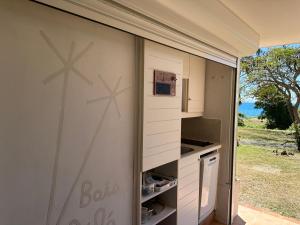 Una cocina con gabinetes blancos y una pared con ventana. en Bois Lélé, en Sainte-Anne