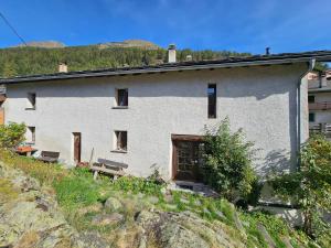 un edificio blanco en una colina con bancos delante en Bourg-saint-Pierre : le cachet d'antan, en Bourg-Saint-Pierre