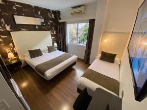 a hotel room with two beds and a tv at Hotel Alvear in Montevideo