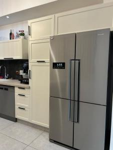 a stainless steel refrigerator in a kitchen with white cabinets at Suite 24/7-סוויטת 24/7 in Ramat Gan