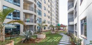 un patio de apartamentos con palmeras y un parque infantil en JVhomes2bedroom-Ndemi gardens en Nairobi
