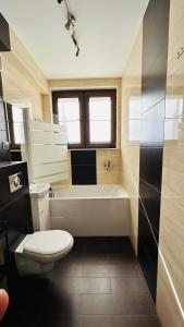 Sopot Marina Beach Suites في سوبوت: حمام مع مرحاض وحوض استحمام ومغسلة
