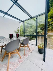 ein Glashaus mit einem Tisch und Stühlen auf einer Terrasse in der Unterkunft Der Vitihof Pastoren Suite in Osnabrück