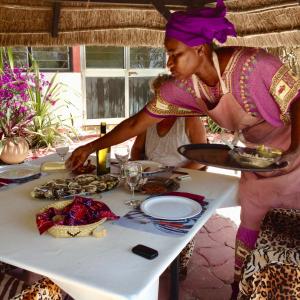 a woman standing over a table with a plate of food at ECOLODGE SAFARI in Cap Skirring