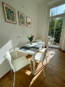 una mesa de comedor blanca con sillas blancas y un jarrón de flores en Mittendrin en Cottbus
